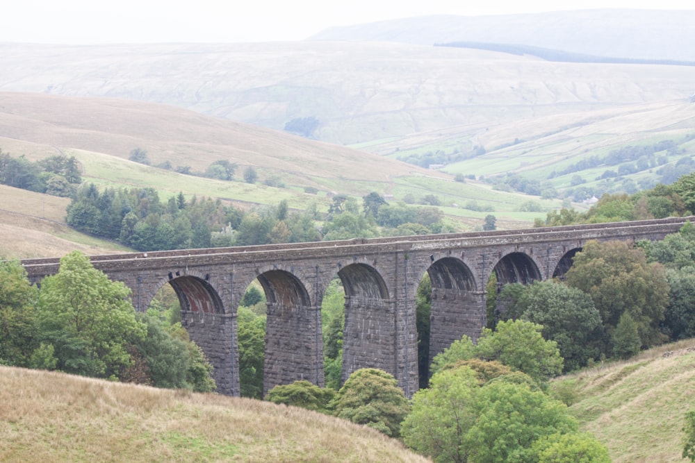 gray concrete bridge over green mountains during daytime