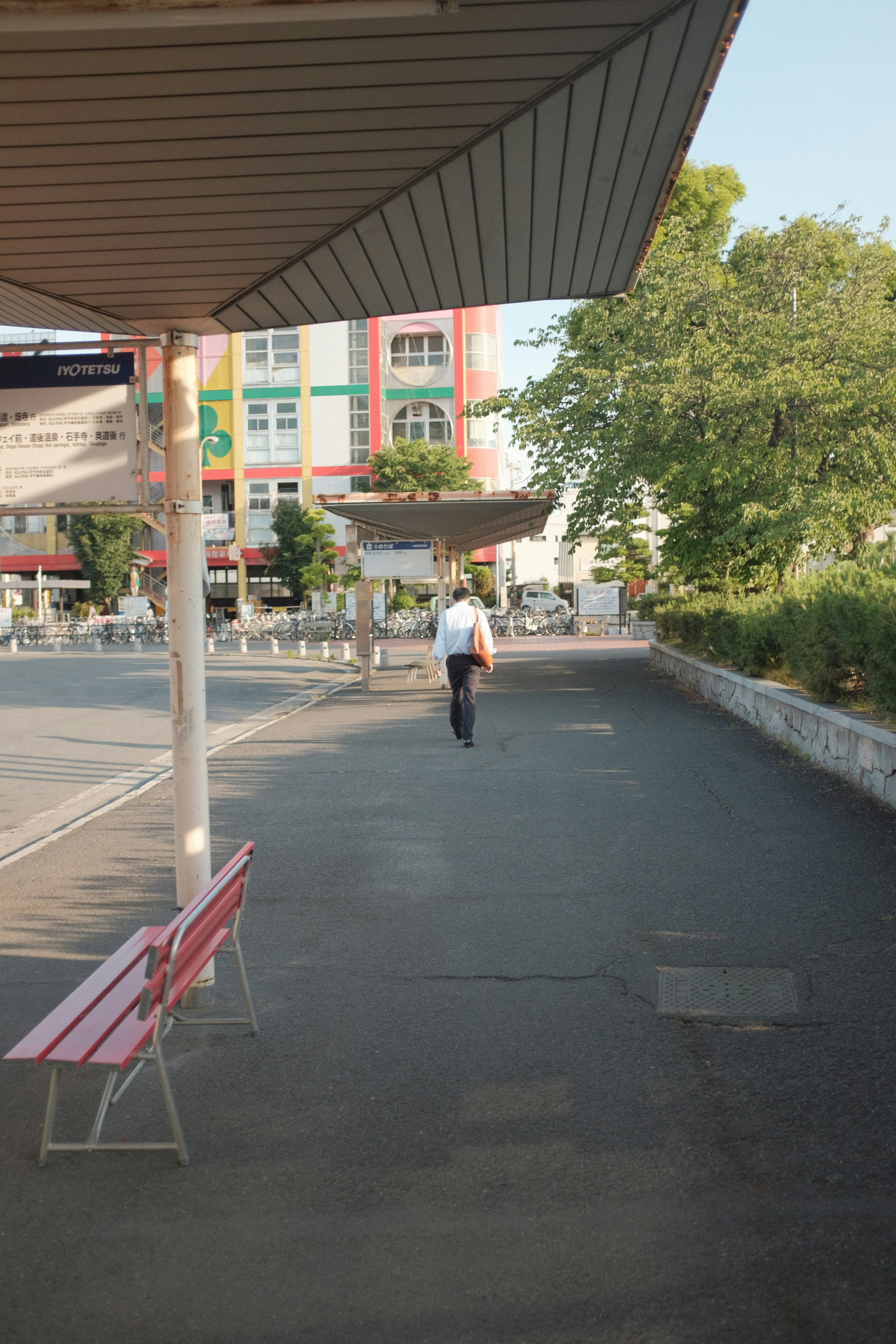 woman in white shirt and black pants walking on sidewalk during daytime