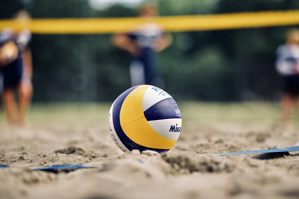 yellow and white volleyball on brown sand during daytime