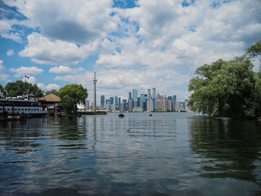 body of water near green trees and buildings under white clouds and blue sky during daytime