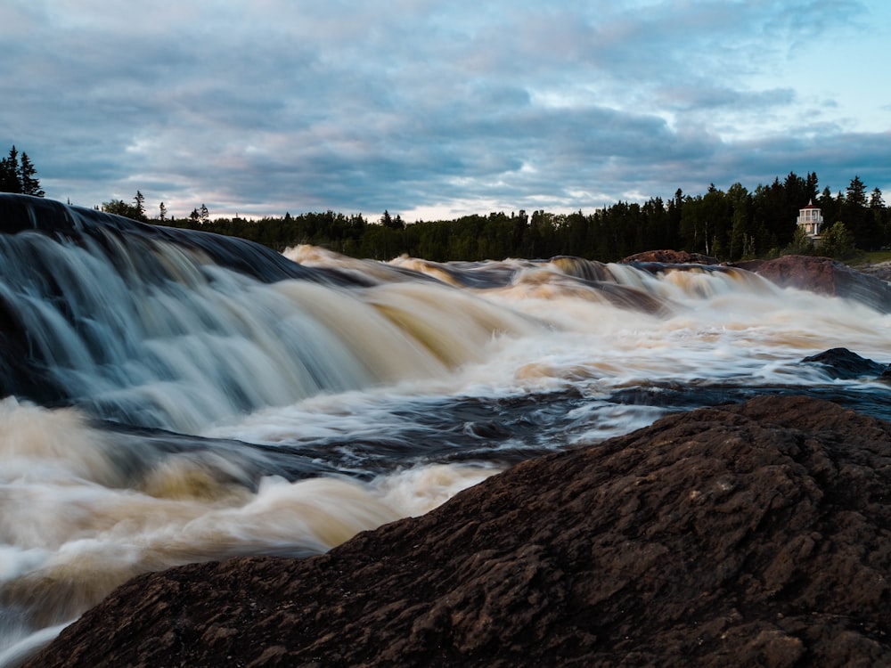 water falls under cloudy sky during daytime