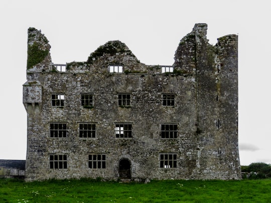 grey concrete building on green grass field in Leamaneh Castle Ireland