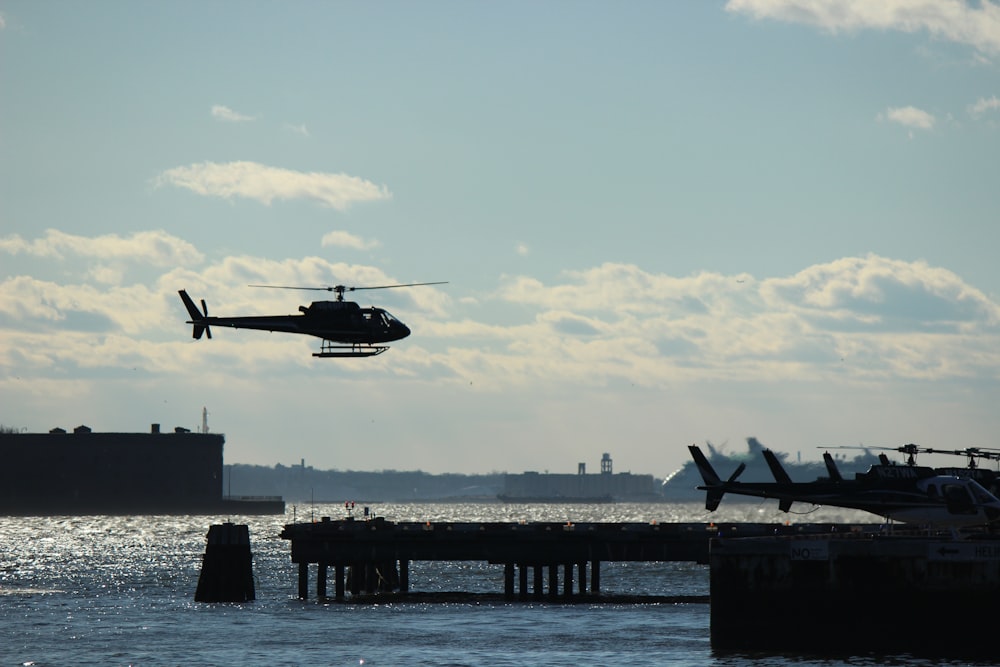 helicóptero preto voando sobre o mar durante o dia