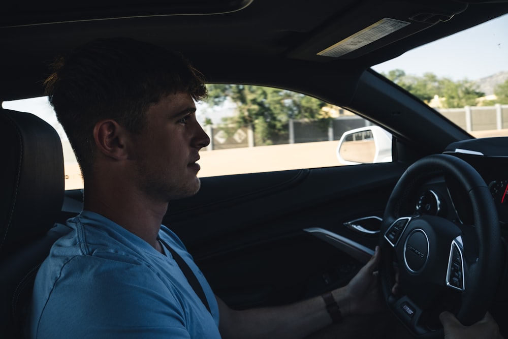 man in blue shirt driving car during daytime