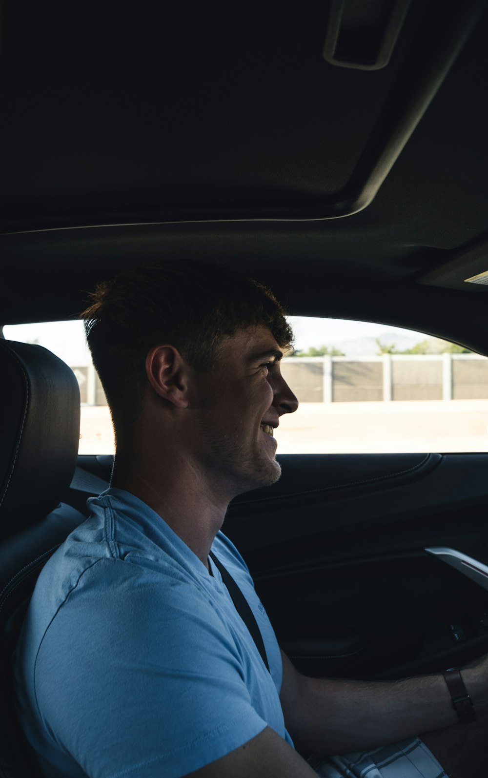 man in blue dress shirt driving car