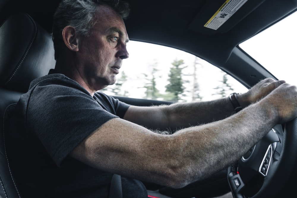 man in black t-shirt driving car during daytime