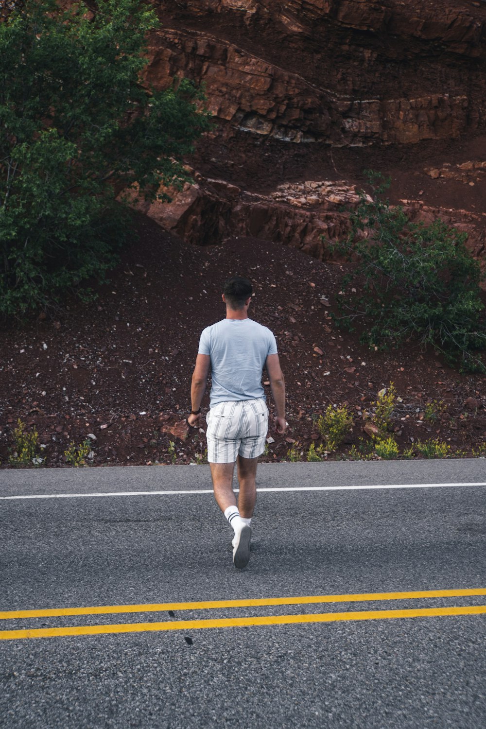 man in white tank top and white shorts standing on road during daytime