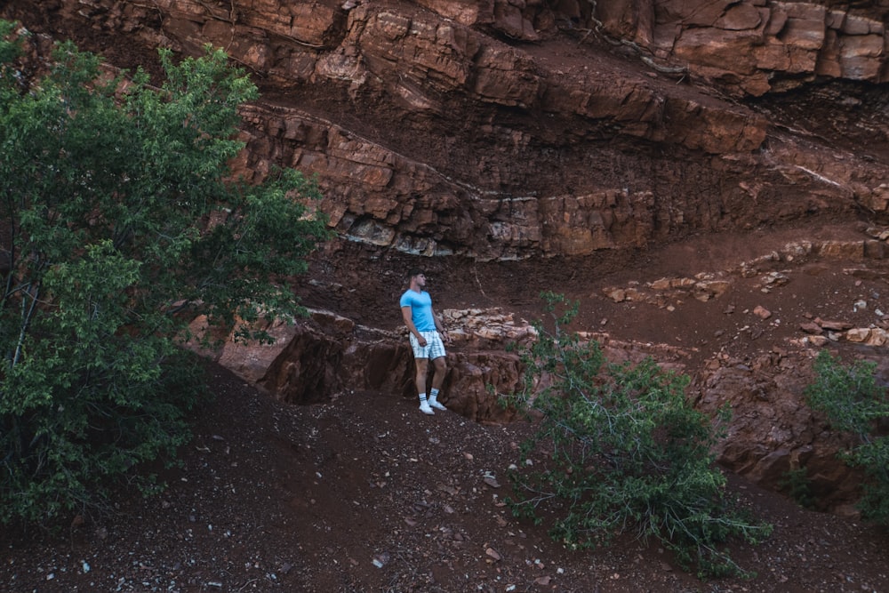 man in blue shirt and white pants walking on dirt road during daytime