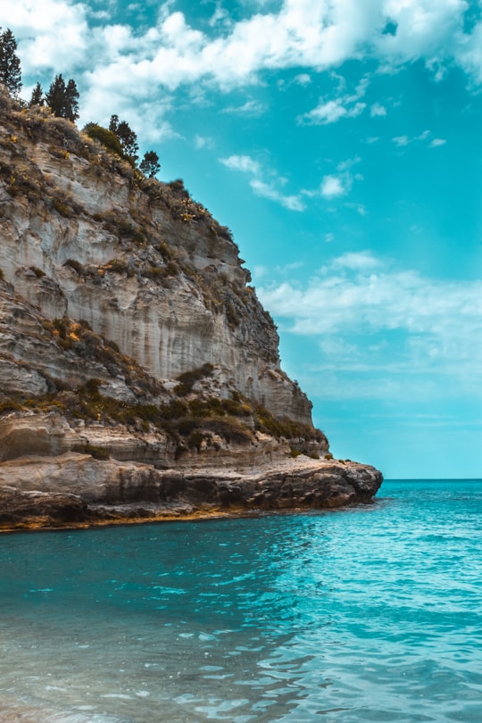 brown rock formation on sea under blue sky during daytime in Tropea Italy