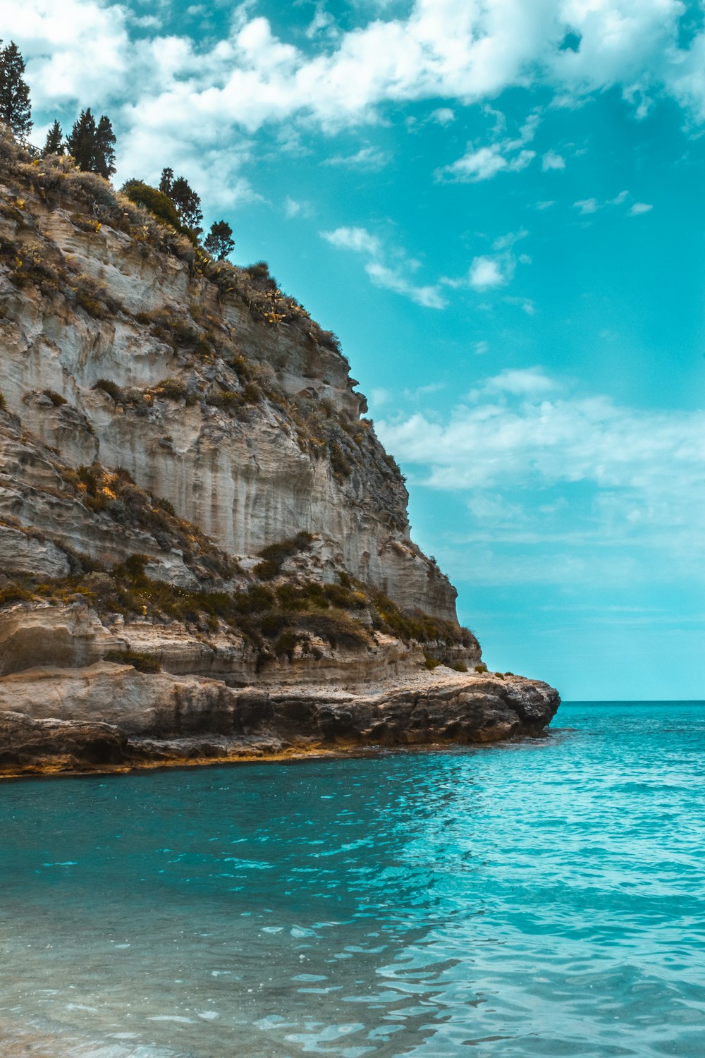 brown rock formation on sea under blue sky during daytime