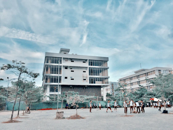 A bright, modern school building with students engaging in outdoor activities under a clear blue sky.