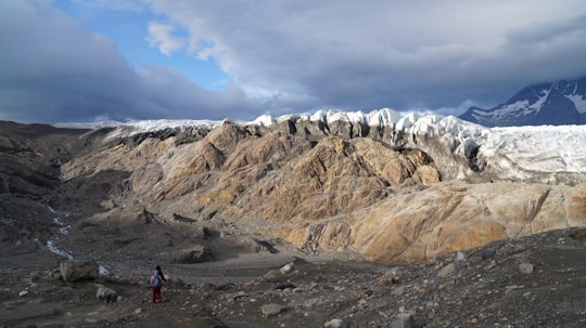 people walking on gray sand near brown mountain under white clouds during daytime in Glaciar Grey Chile