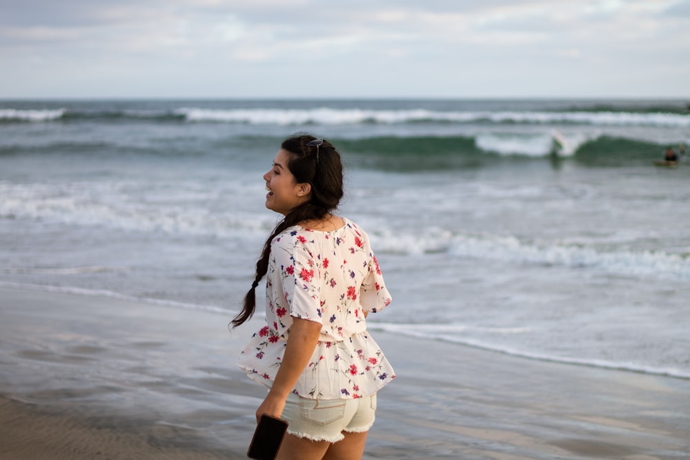 girl in white and pink floral dress standing on beach during daytime