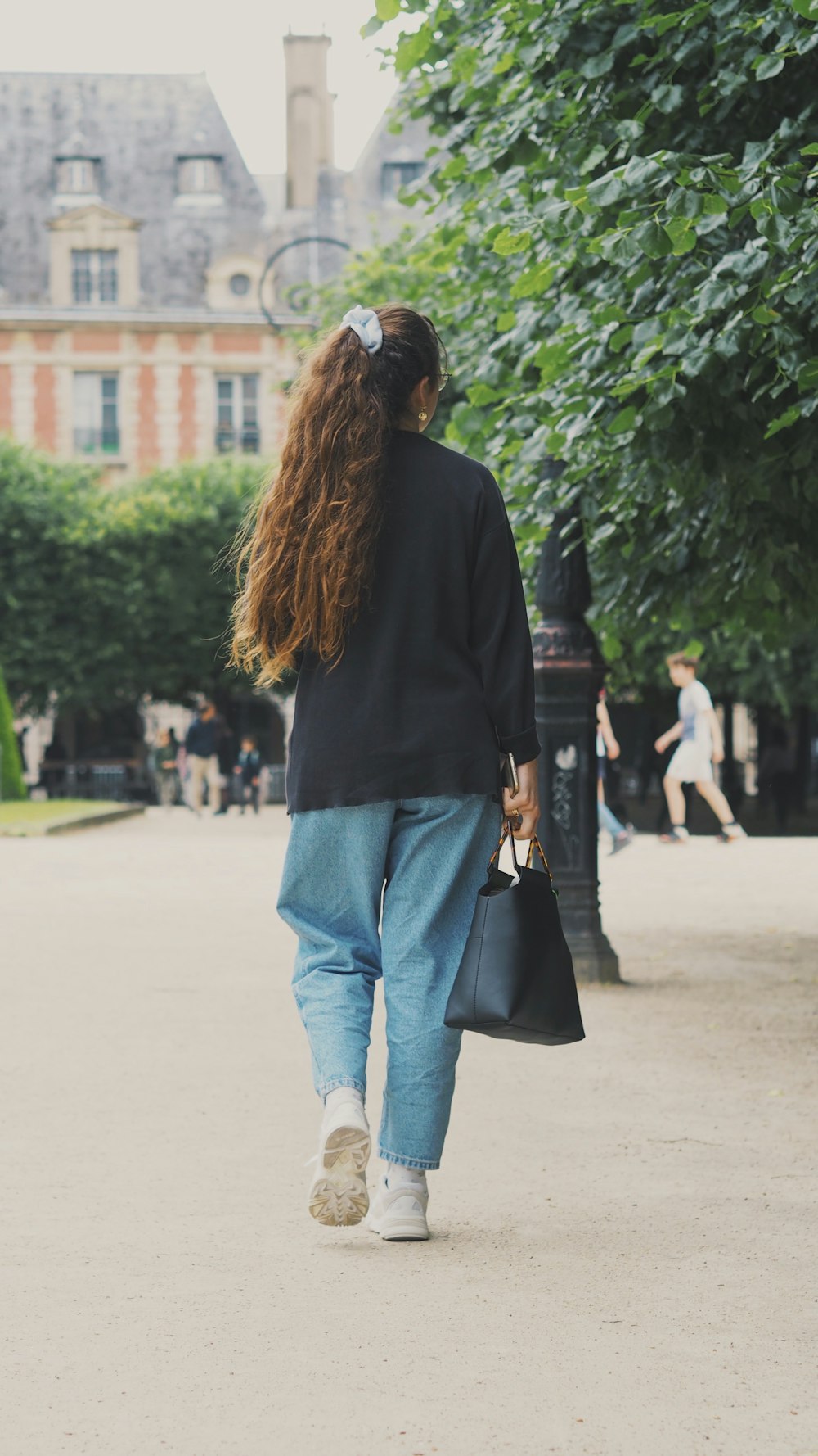 woman in black long sleeve shirt and blue denim jeans standing on gray concrete floor during