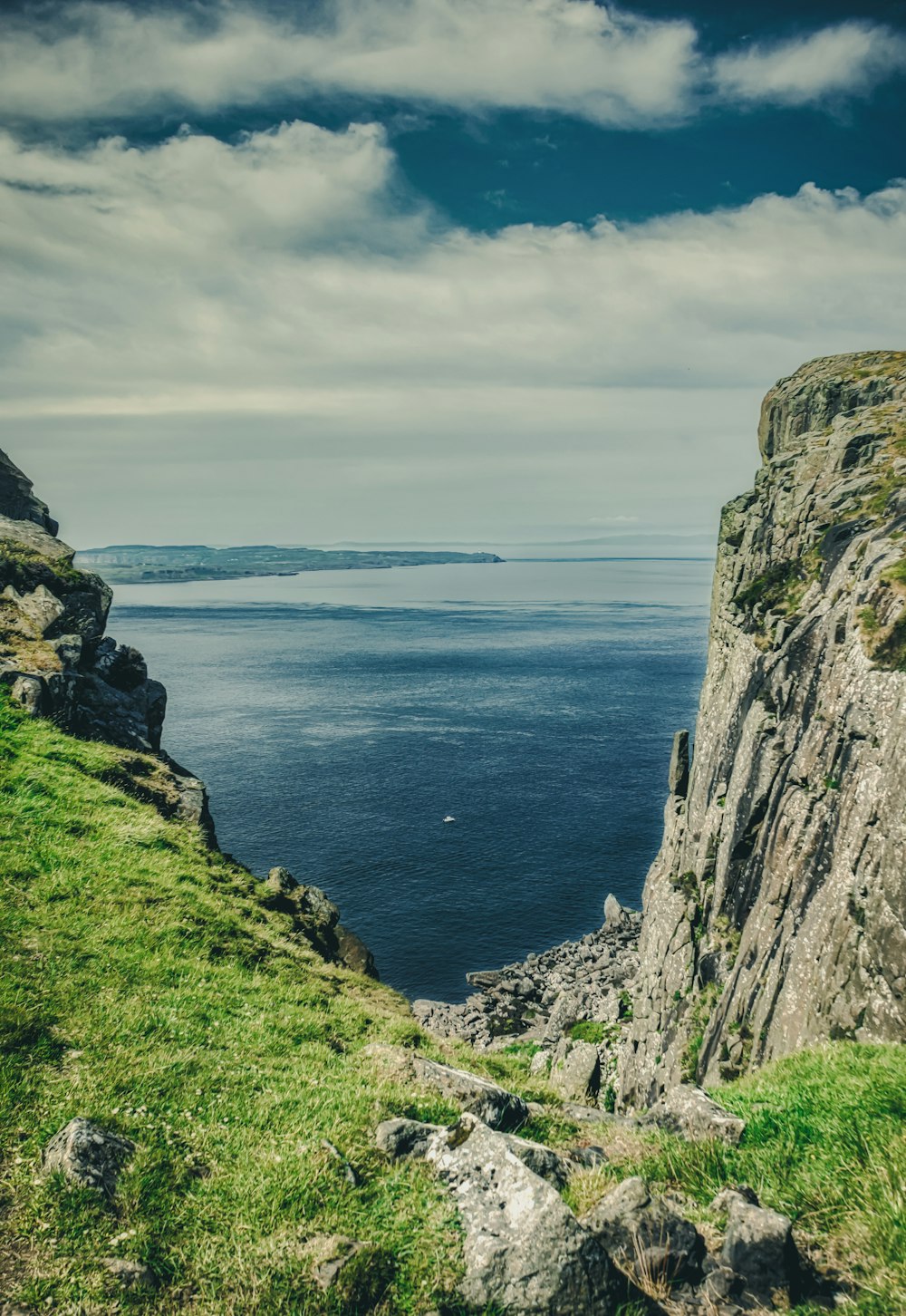 green and brown rock formation beside blue sea under white clouds during daytime