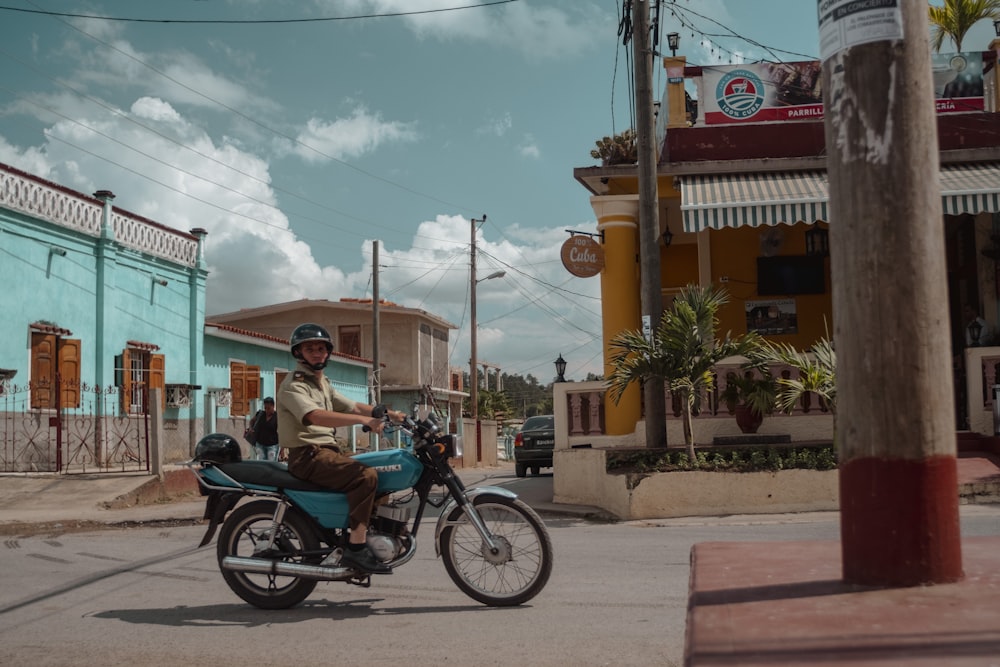 man in blue shirt riding blue motorcycle during daytime