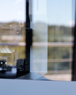 A close-up view of a computer's internal components, including a motherboard and cooling system. The image captures reflections of the surroundings on the glass panel of the computer case, adding a layer of complexity to the scene. The focus is on the intricate details of the hardware.