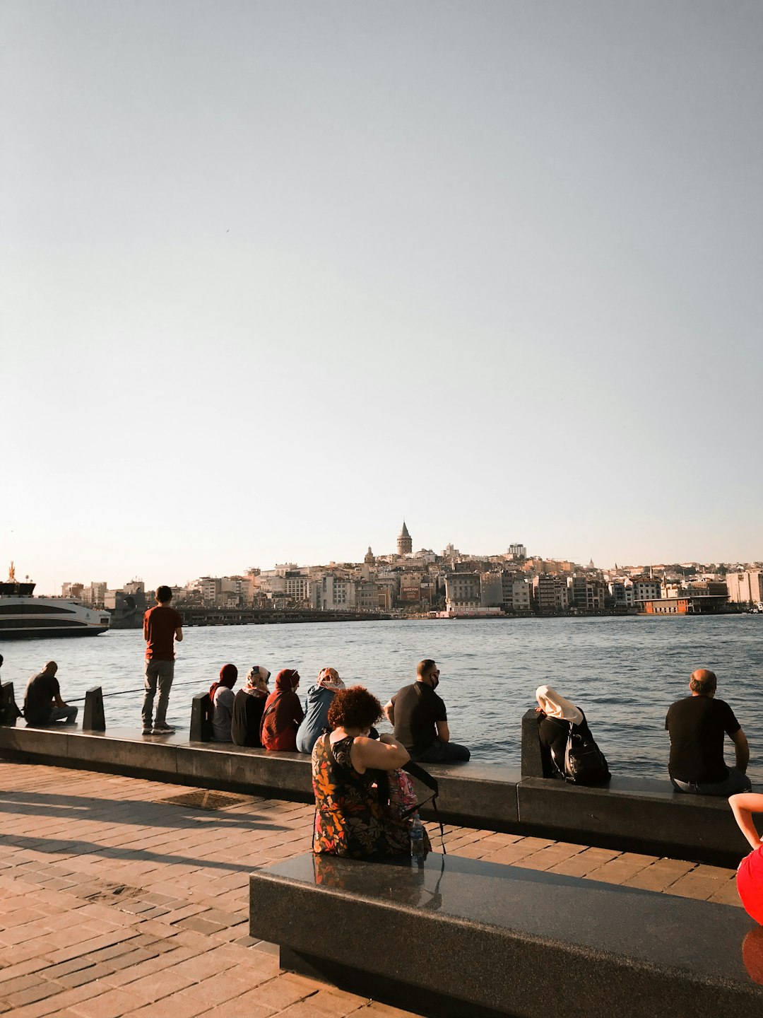 people sitting on brown wooden bench near body of water during daytime