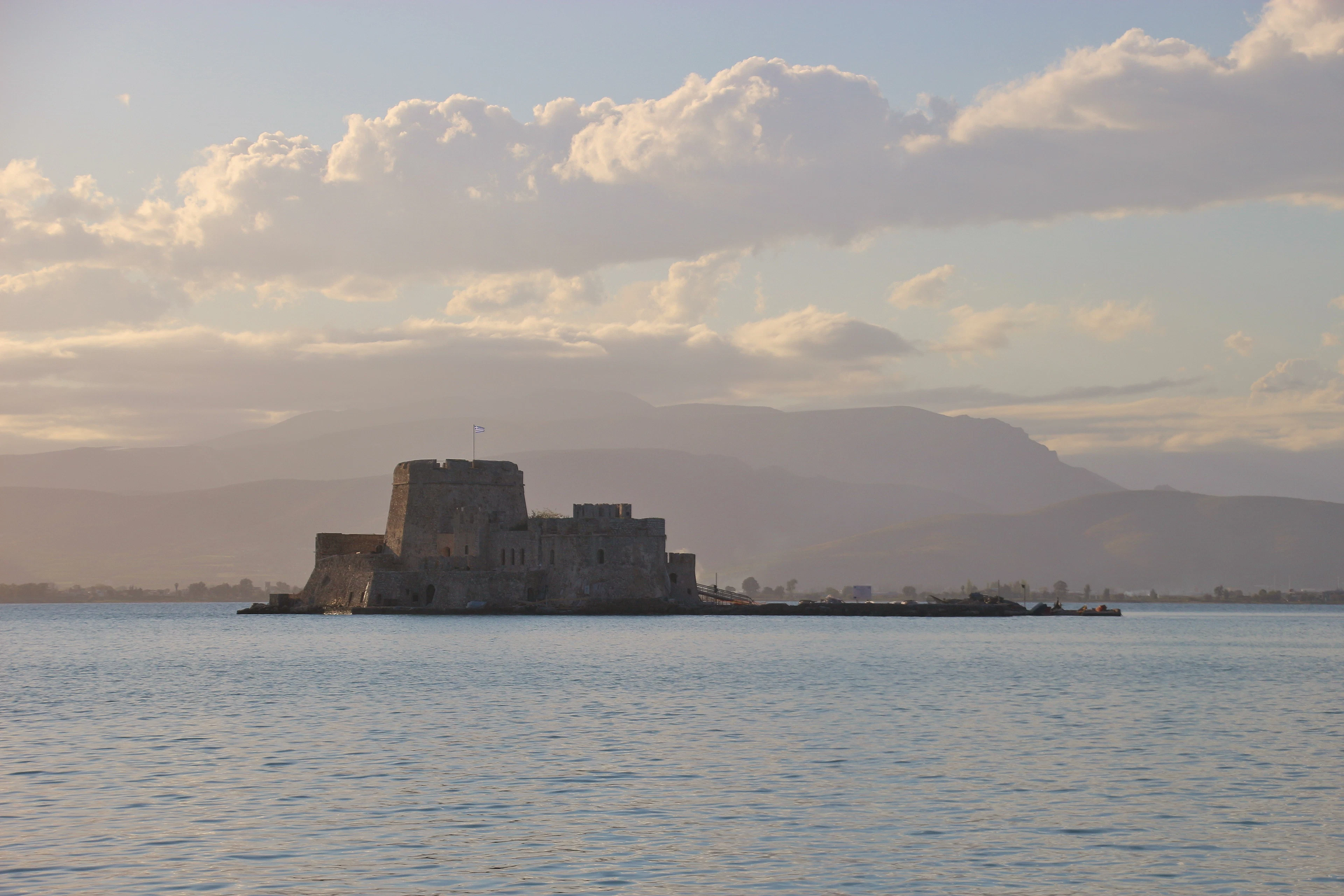 The Bourtzi fortress in the bay of Nafplio shortly before sunset, with pastel mountains beyond