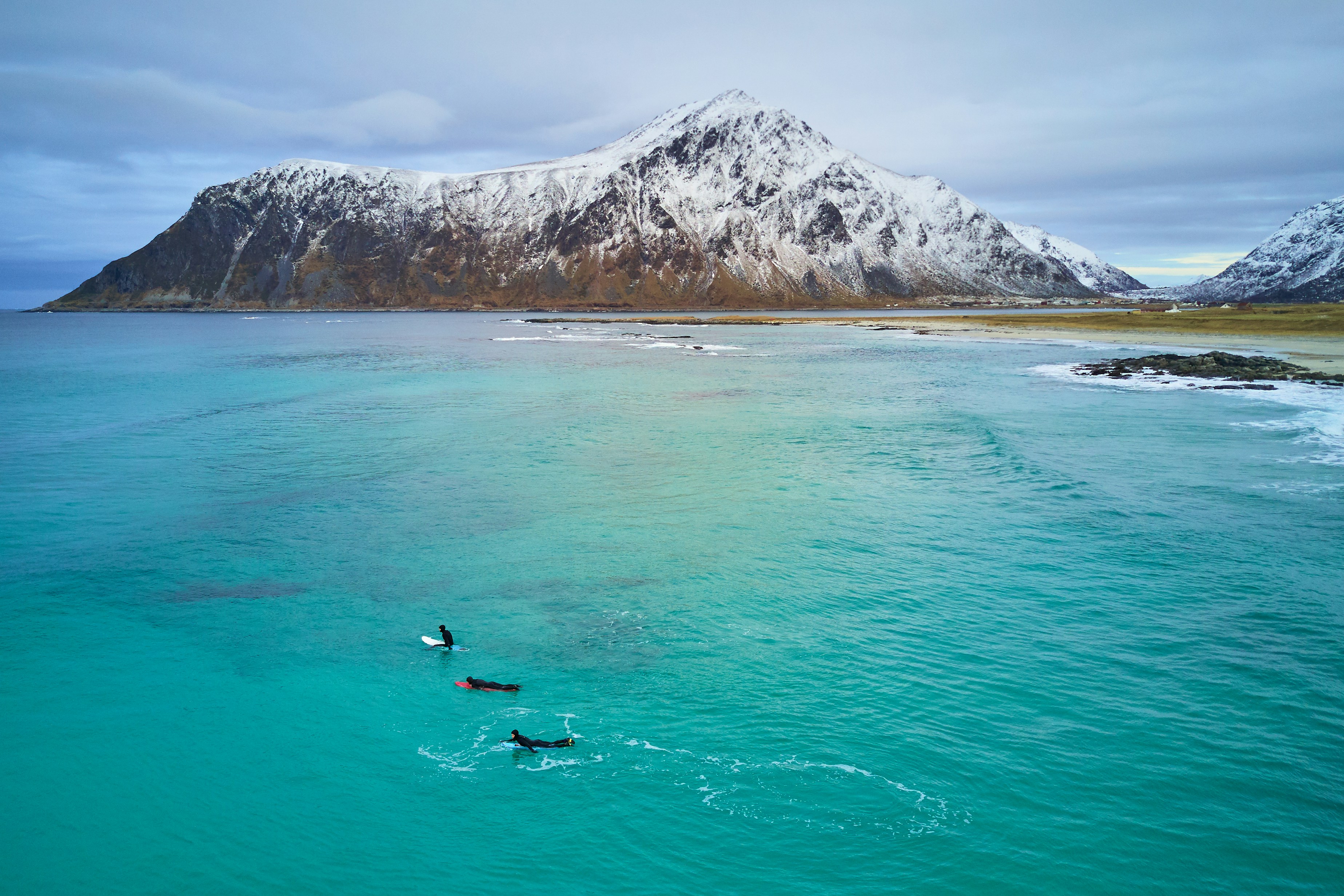 person surfing on sea near mountain during daytime