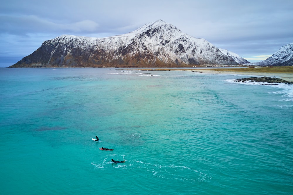 person surfing on sea near mountain during daytime