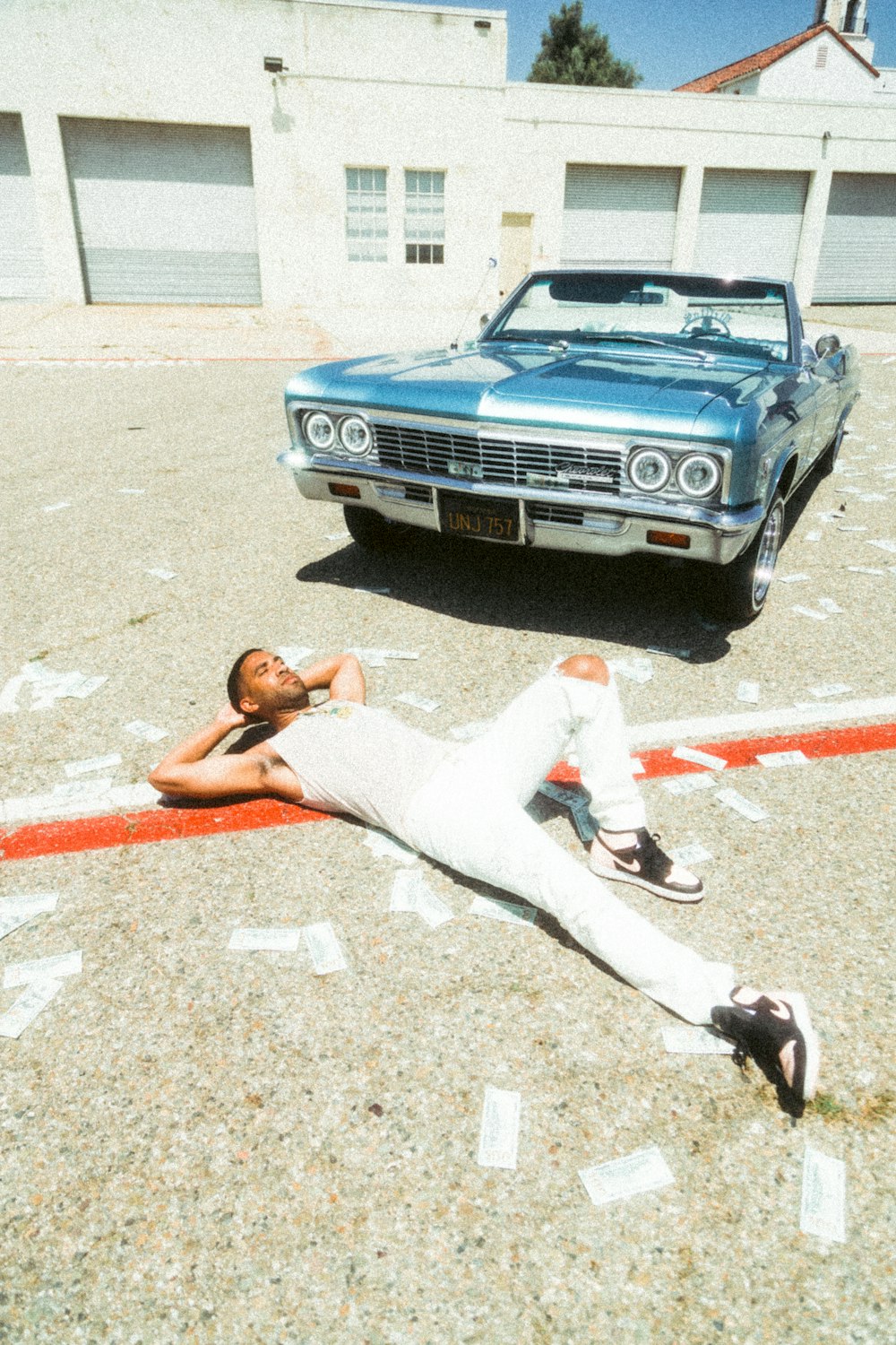 woman in white pants lying on gray asphalt road during daytime