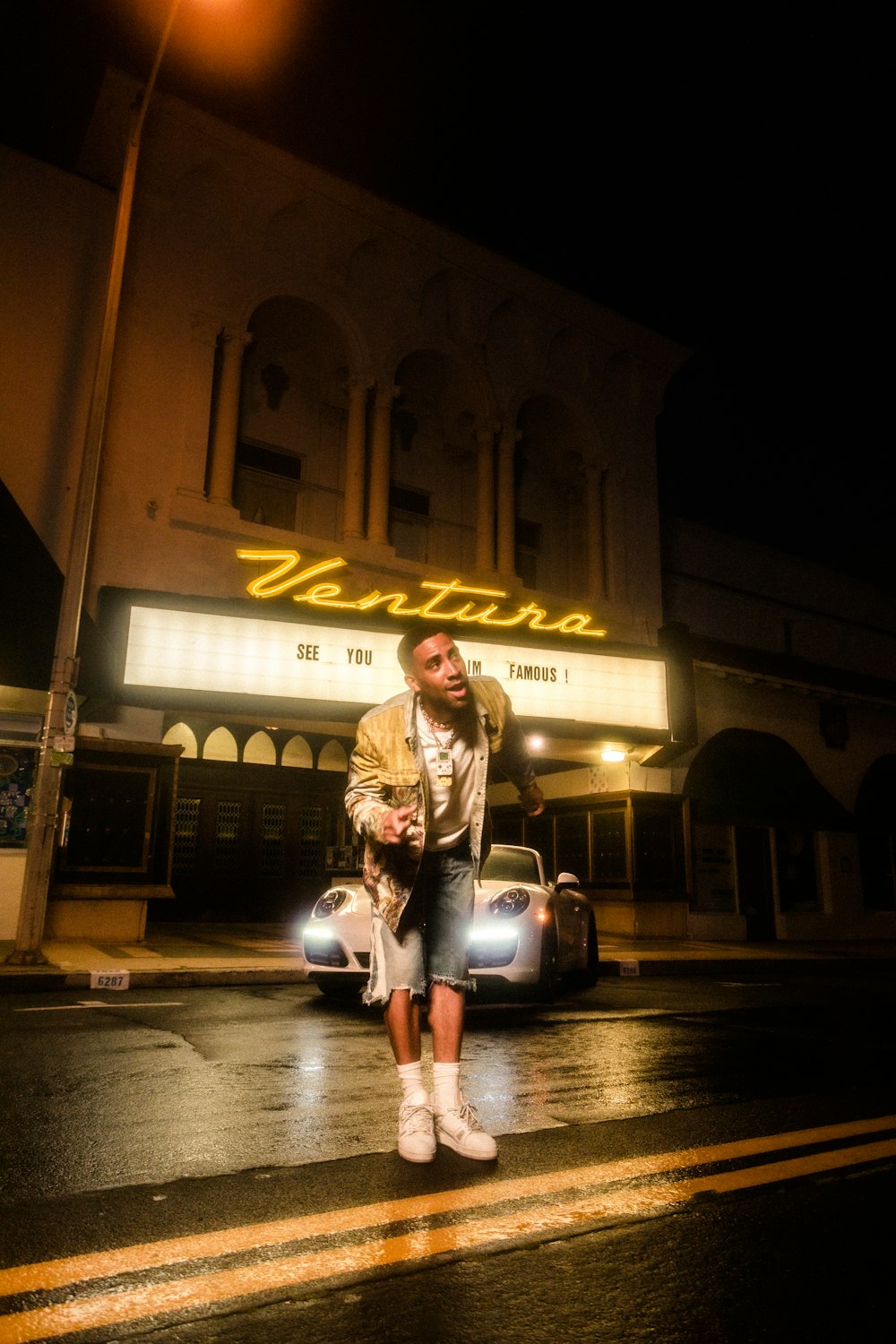 woman in white and black plaid dress shirt standing beside gray car during night time