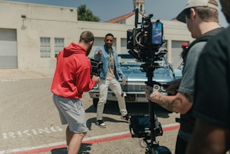 man in red polo shirt and gray shorts standing beside man in blue denim jacket during