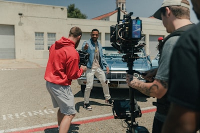 man in red polo shirt and gray shorts standing beside man in blue denim jacket during