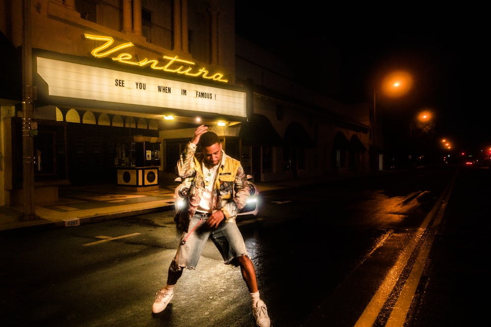 man in black and white jacket standing on road during night time