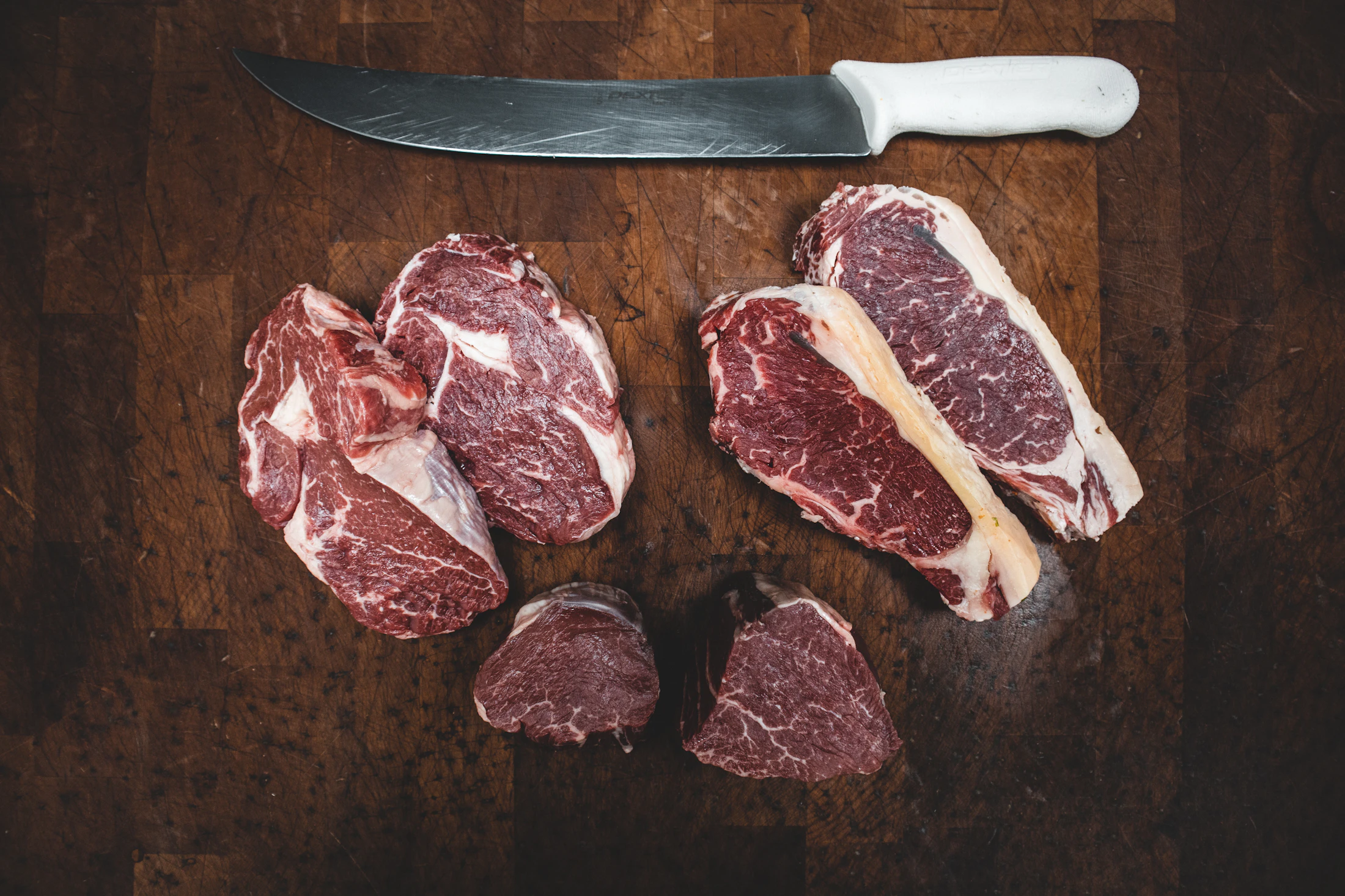 Raw dry aged steaks on a butcher's board