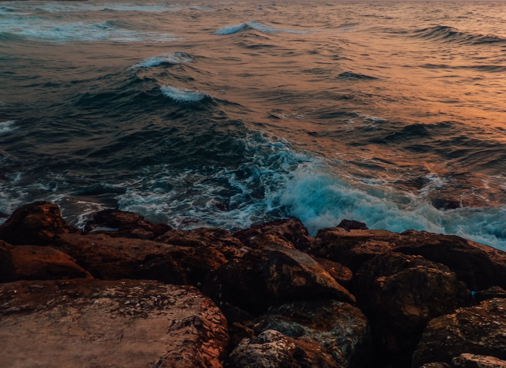 日中に海の波が岩に打ち寄せる茶色の岩だらけの海岸