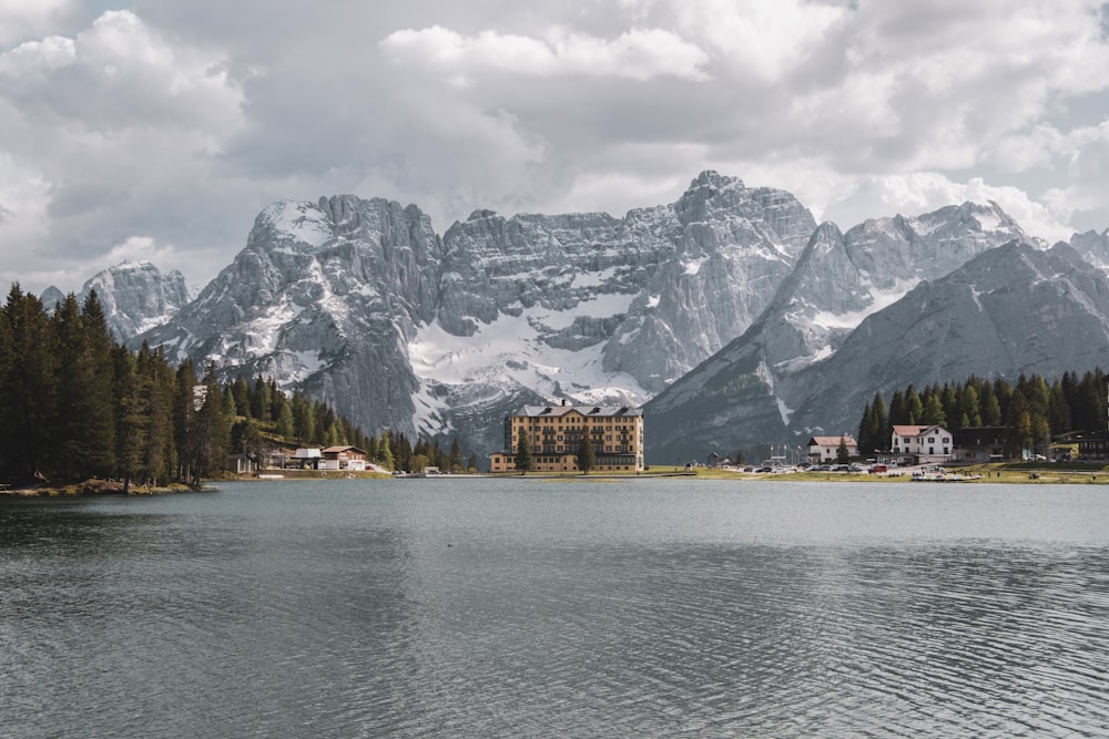 brown and white building near body of water and snow covered mountain during daytime