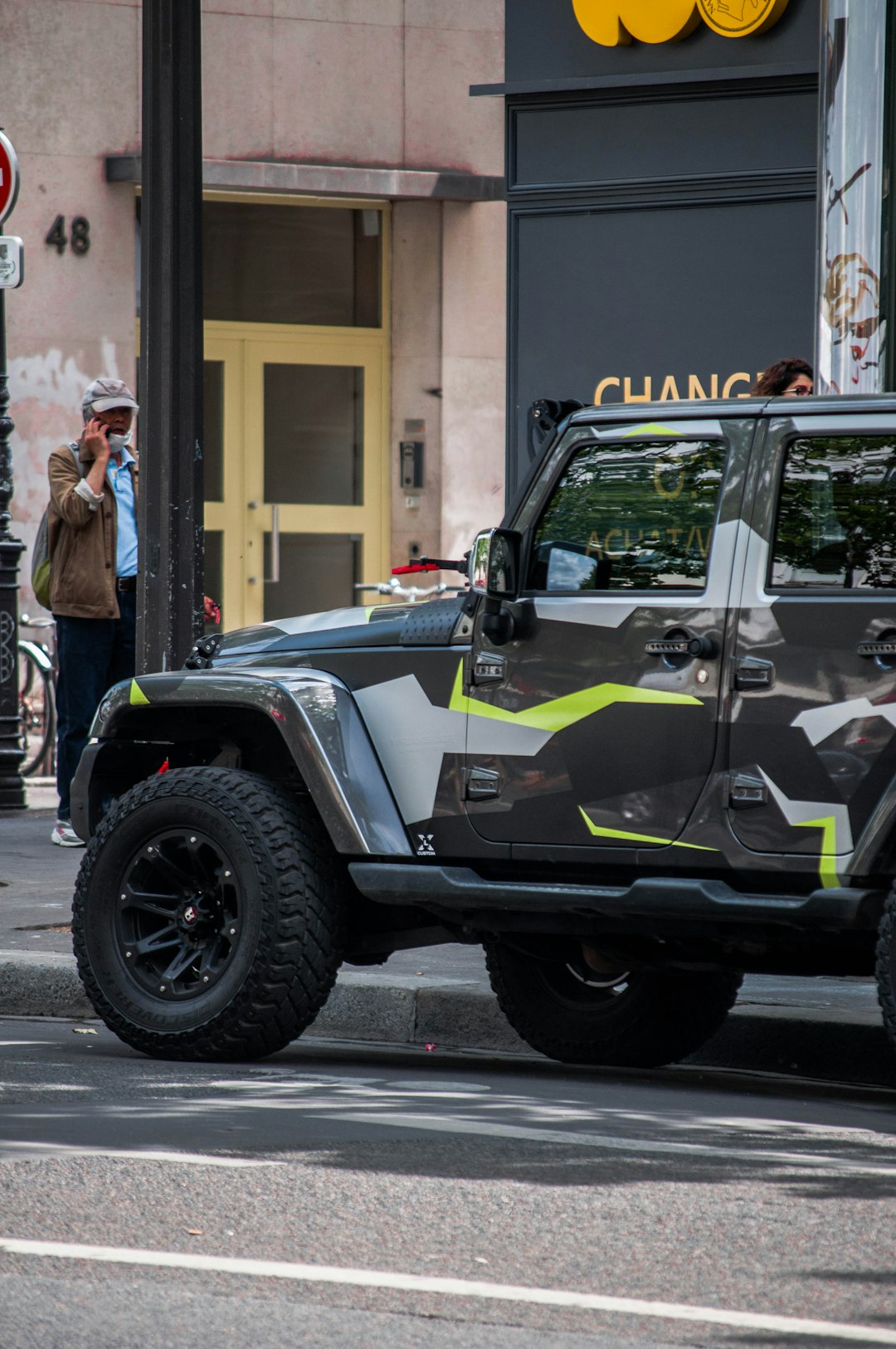 green and black jeep wrangler parked on sidewalk during daytime