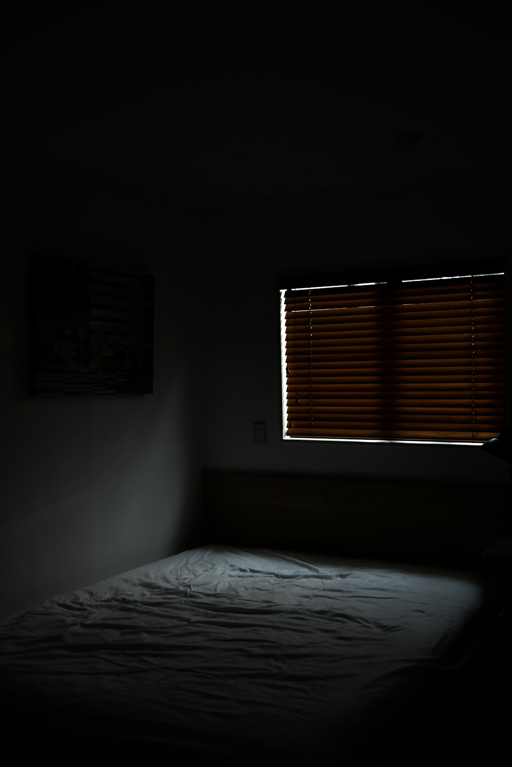 cama branca perto da janela com persianas marrons