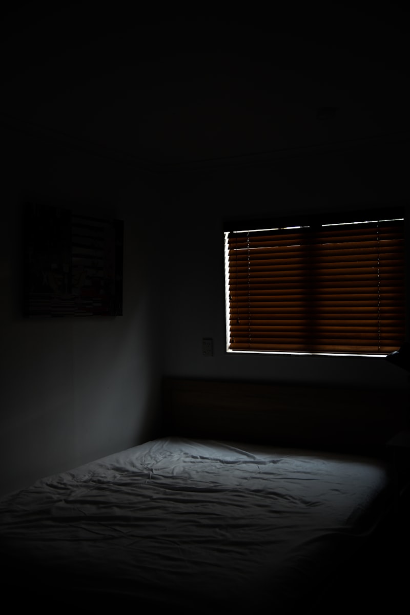 Bett neben einem Fenster mit Jalousien
