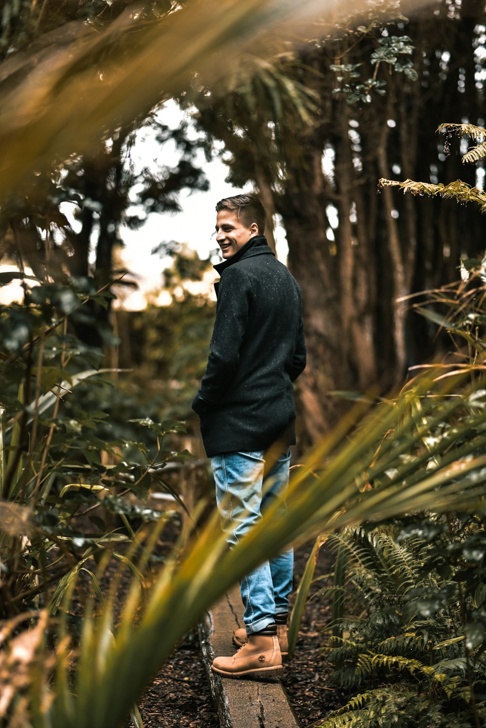 man in black jacket standing near green plants during daytime