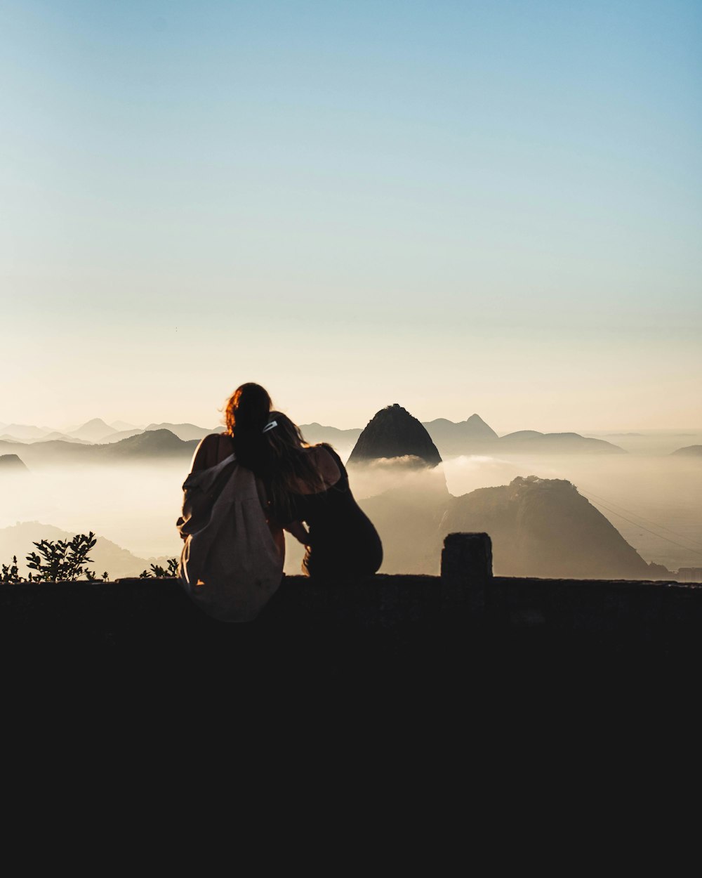 silhouette of man sitting on rock during sunset