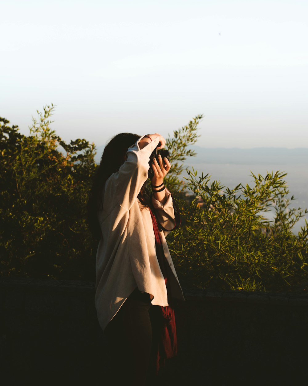 woman in brown coat covering her face with her hand