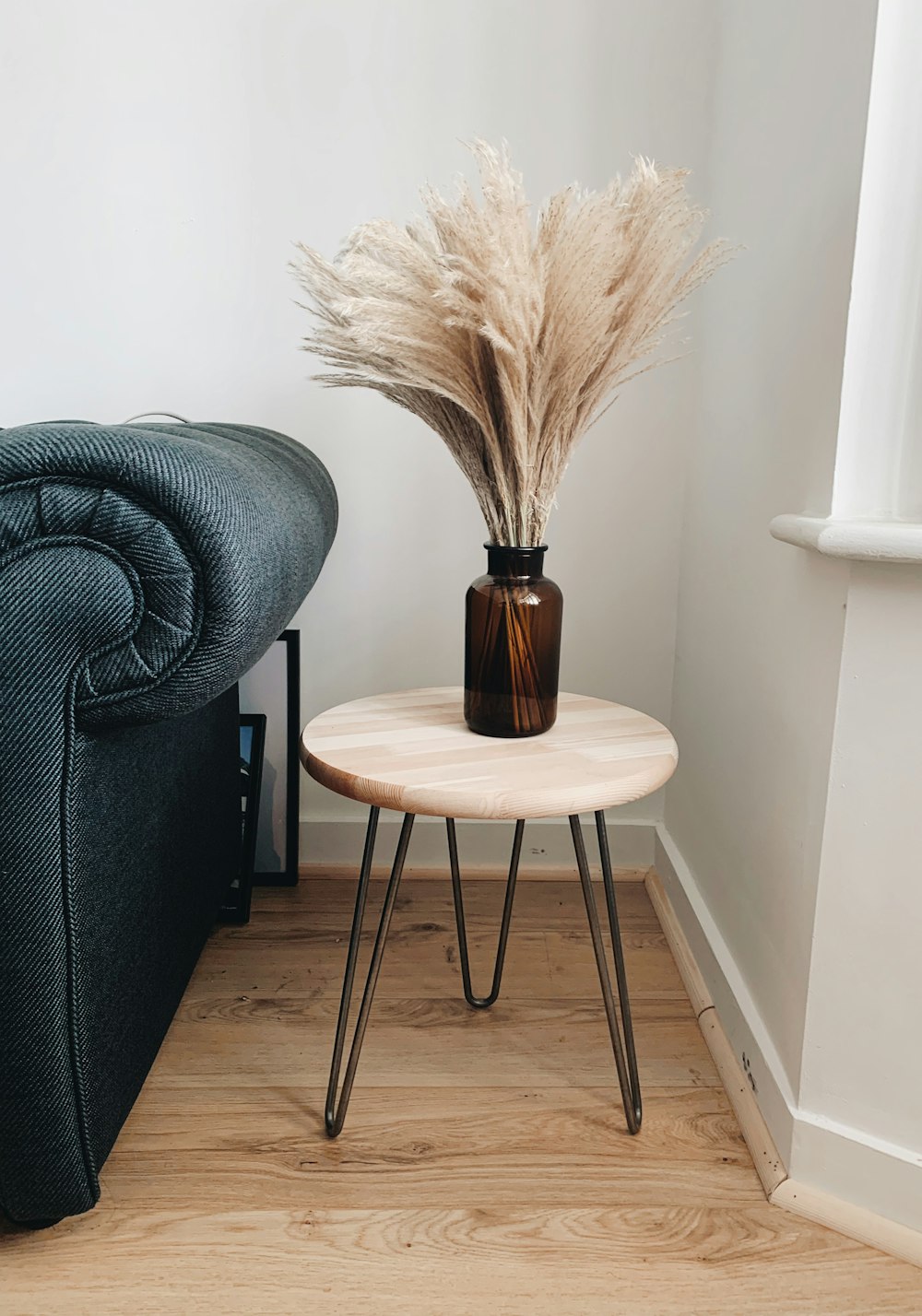 Asiento redondo de madera marrón junto al sofá gris