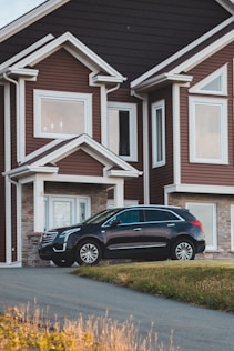 black suv parked in front of white wooden house
