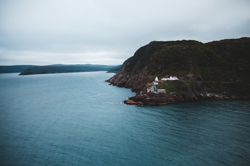 green and brown mountain beside sea under white sky during daytime