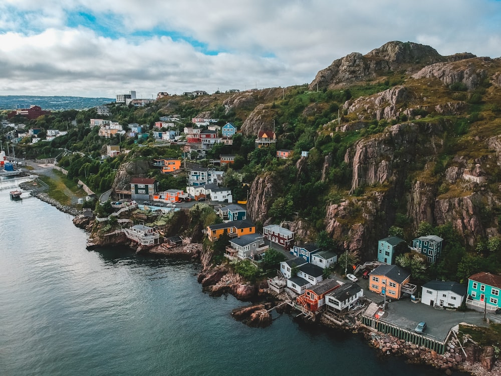 houses on mountain beside body of water during daytime