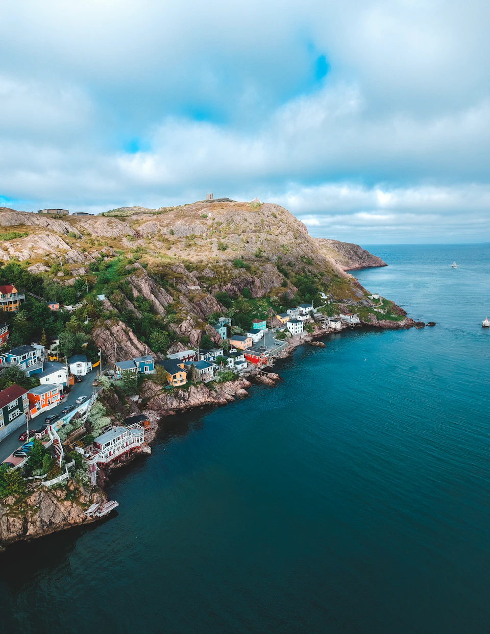 Coastal town perched on rocky cliff overlooking ocean, with buildings at varying heights