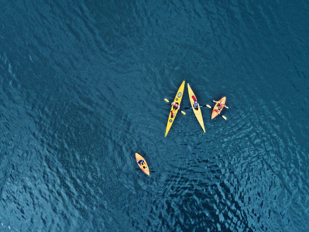 people riding yellow and blue kayaks on body of water during daytime
