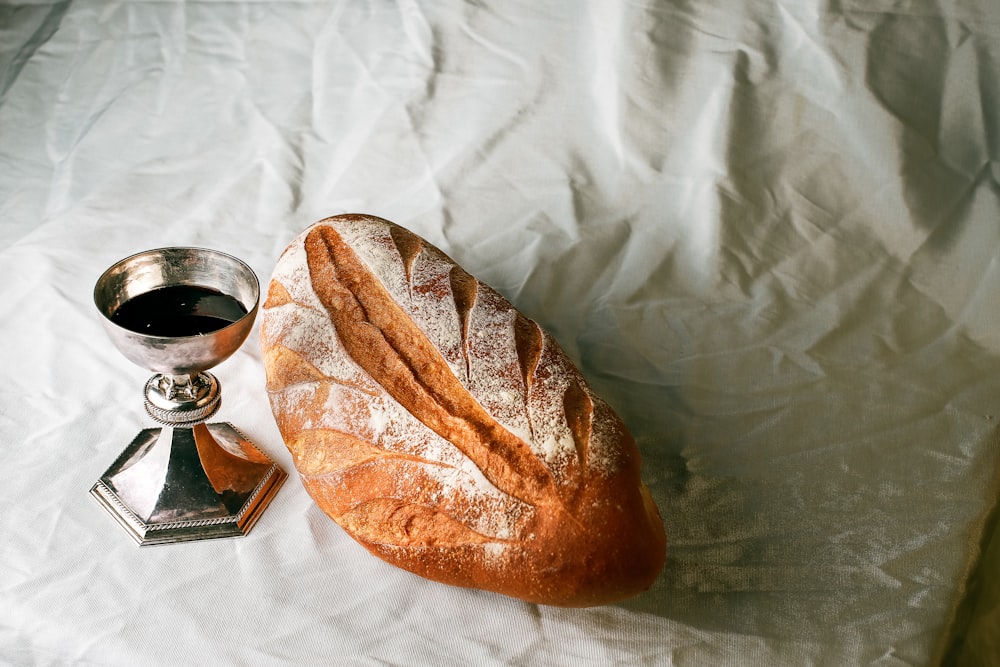 透明なガラスのマグカップの横の白い布地にパン