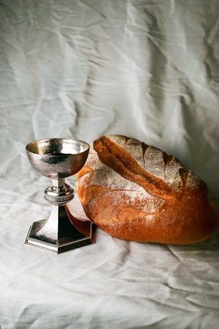 bread on white textile beside stainless steel footed bowl