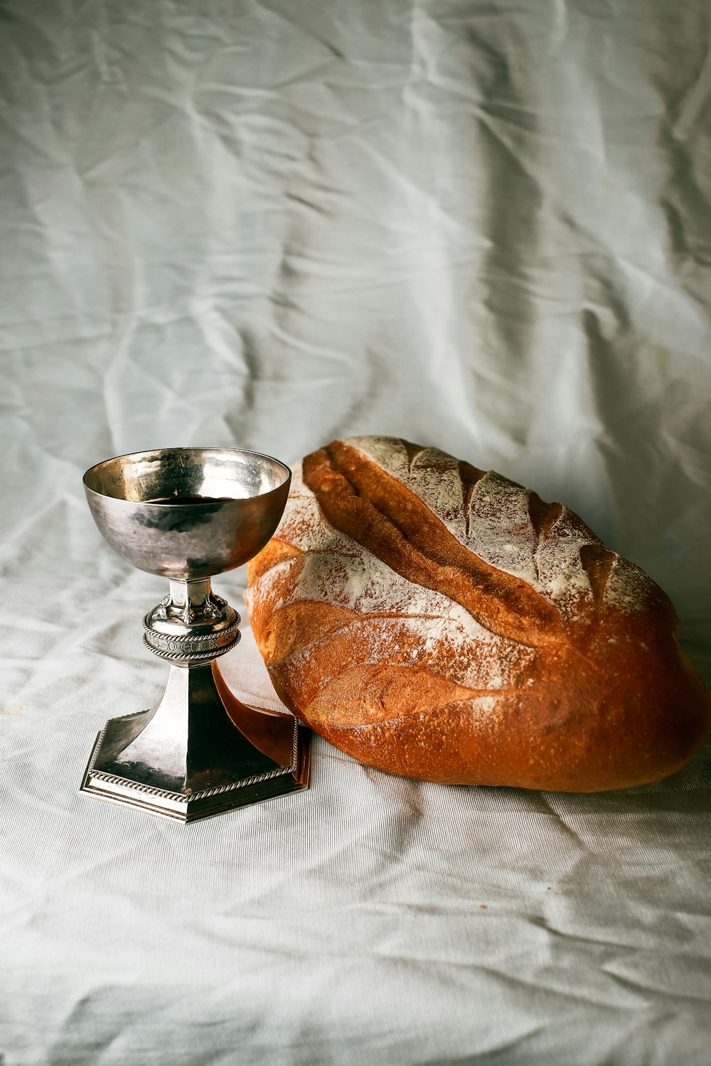 bread on white textile beside stainless steel footed bowl