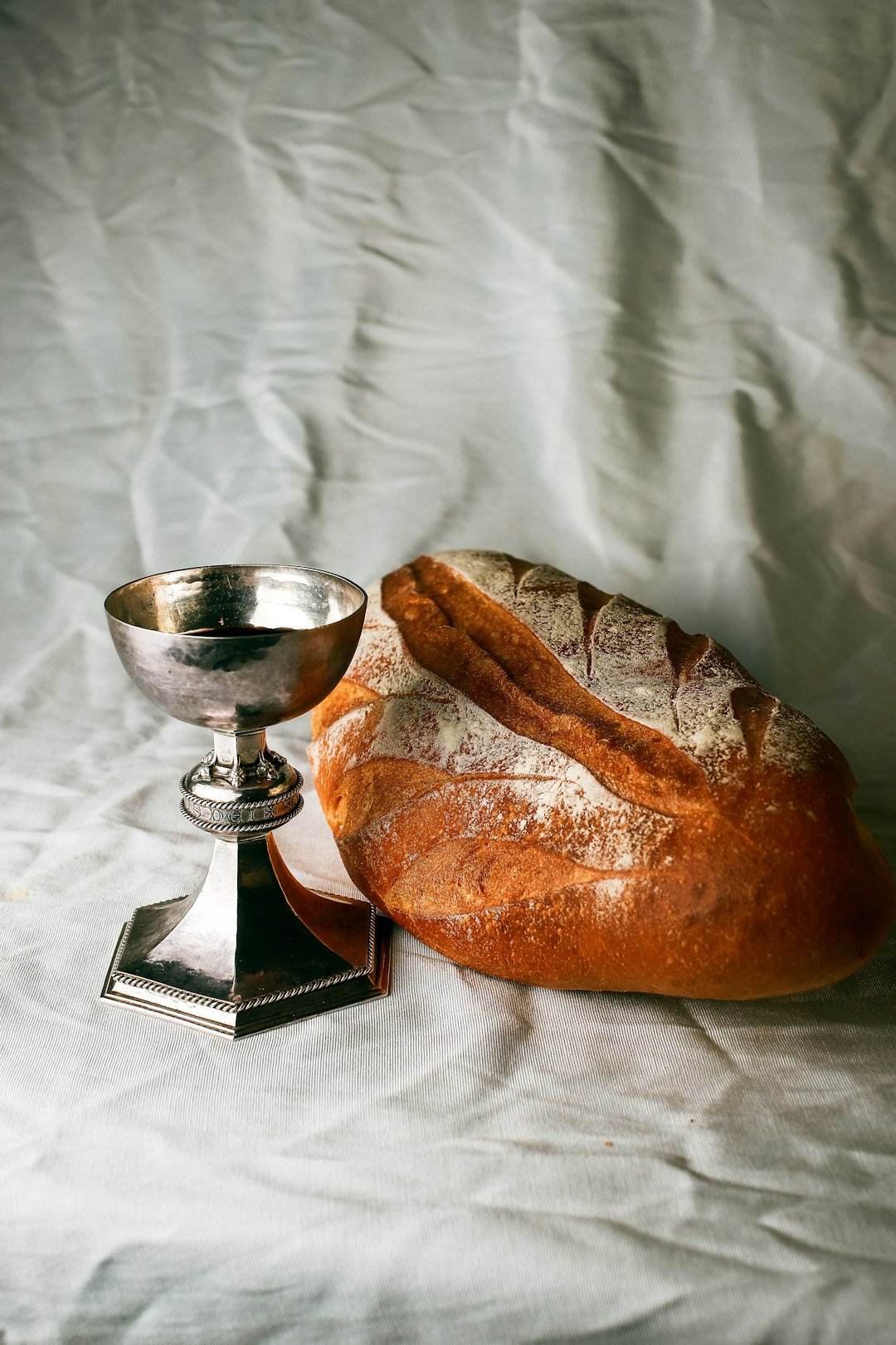 bread on white textile beside stainless steel footed bowl