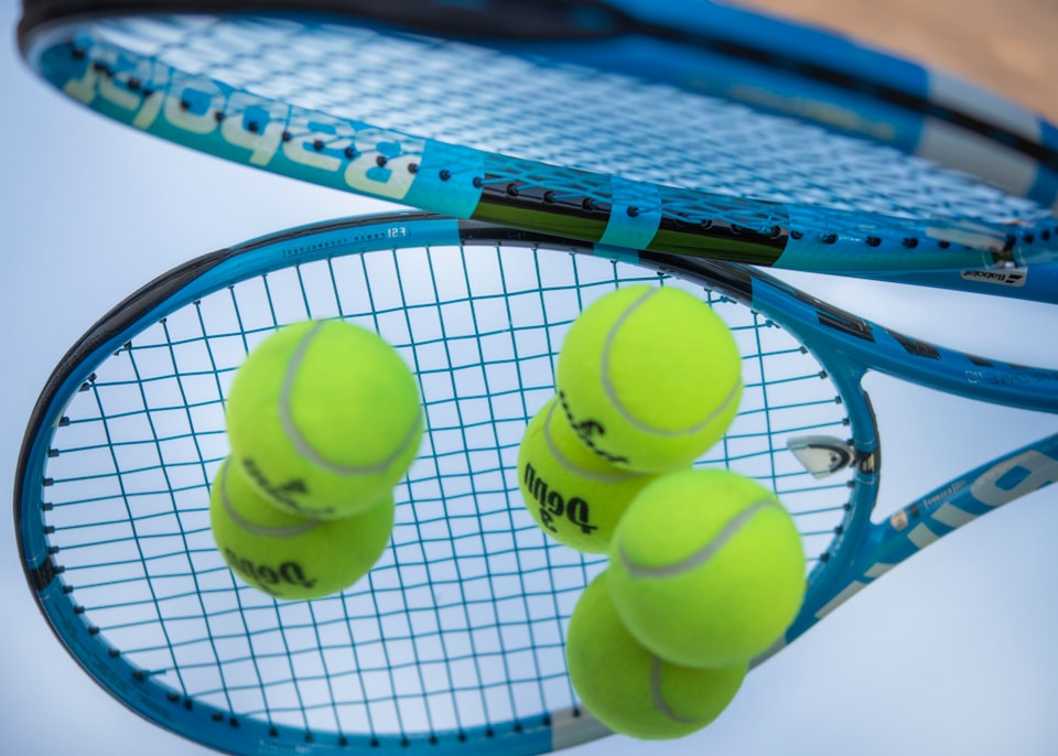 close-up of tennis racket hitting multiple tennis balls